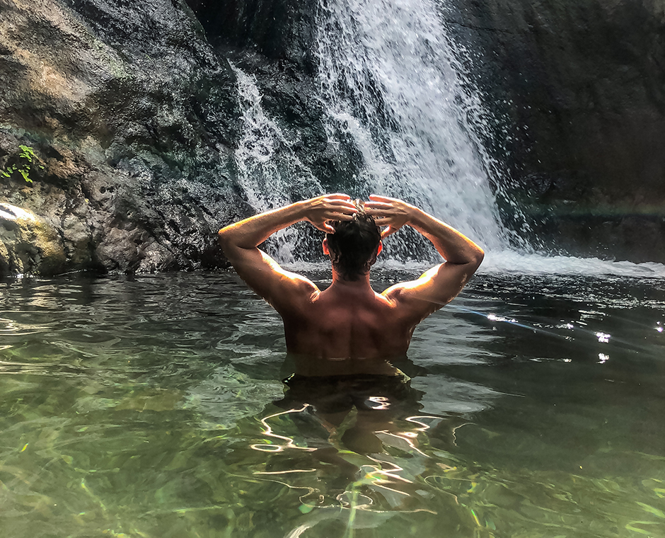 Rückansicht eines Mannes vor einem See mit Wasserfall