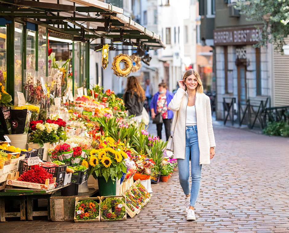 Una ragazza passeggia sorridendo a piazza delle Erbe in centro a Bolzano