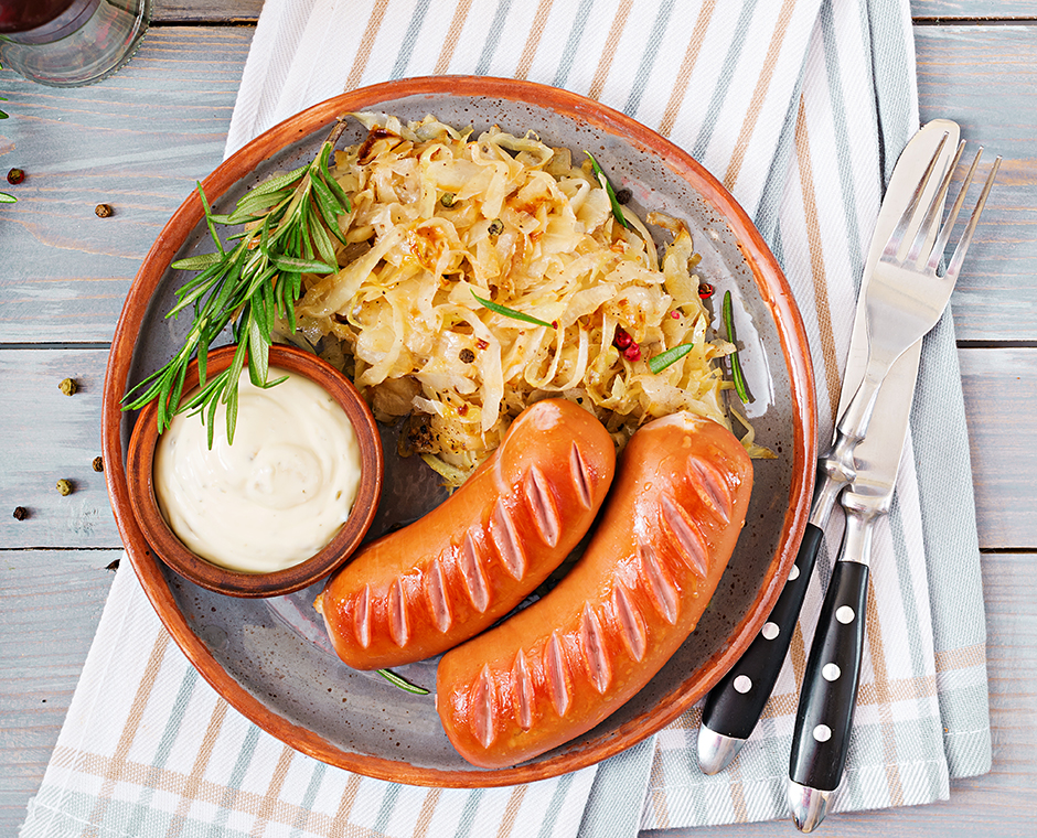 Piatto di salsicce e crauti su tavolo di legno.
