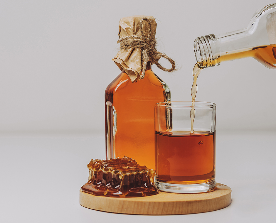 Un bicchiere e una bottiglia di grappa al miele