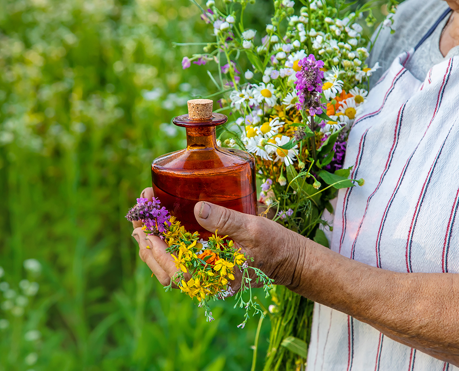 Una persona che ha in mano la bottiglia di grappa alle erbe alpine