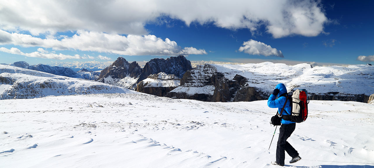 Un escursionista di montagna con attrezzatura da alpinista sulle cime innevate delle Dolomiti